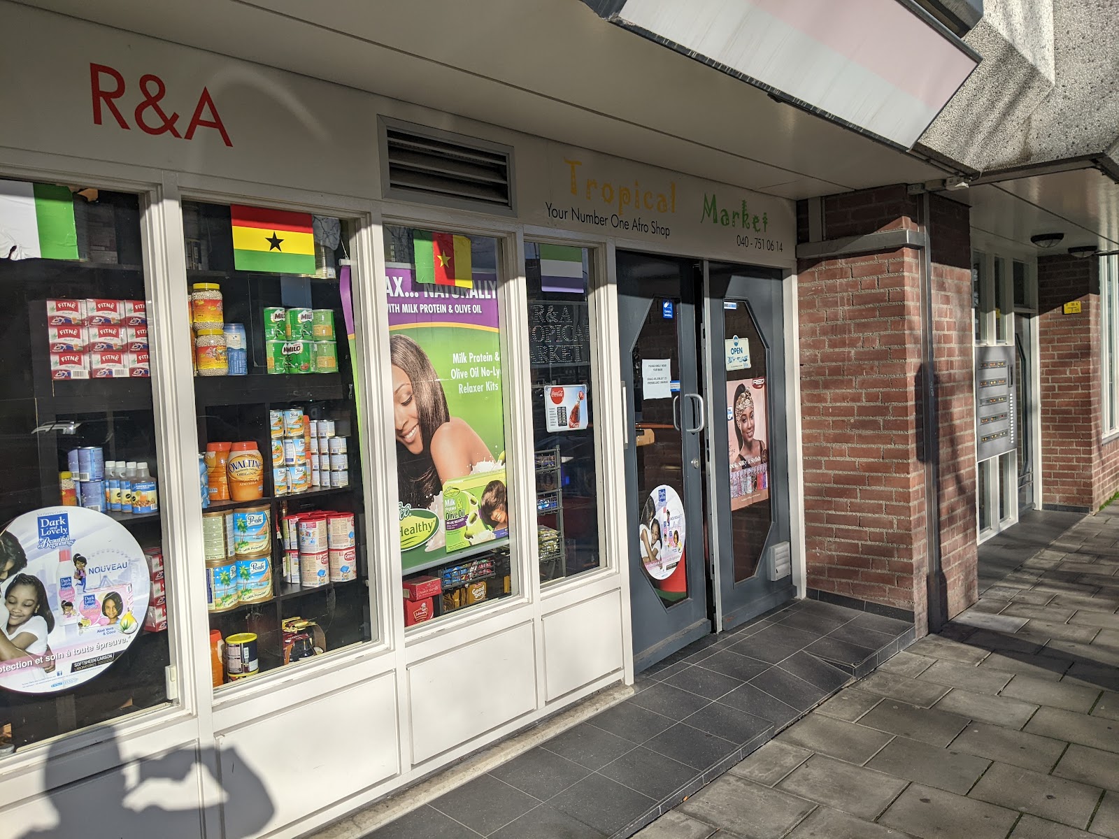 De winkelpui van Excellence Tropical Market in Eindhoven met de Ghanese vlag en een etalage vol producten